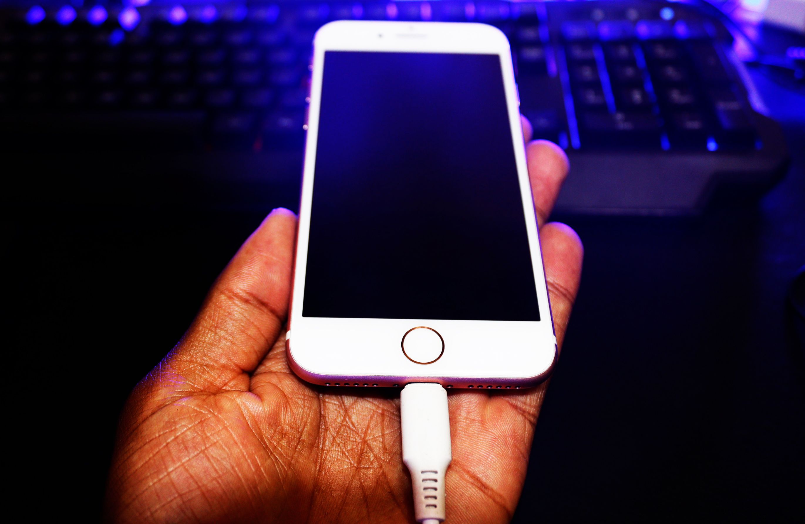 An iPhone being held in the hand with the charger inserted