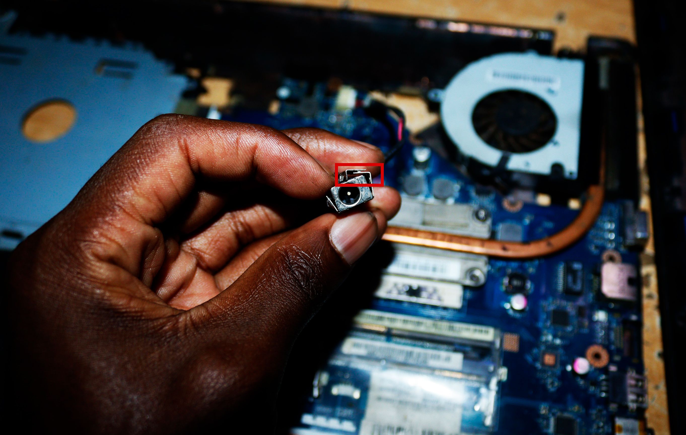 Demonstration of the metal plates holding the charging port of a laptop